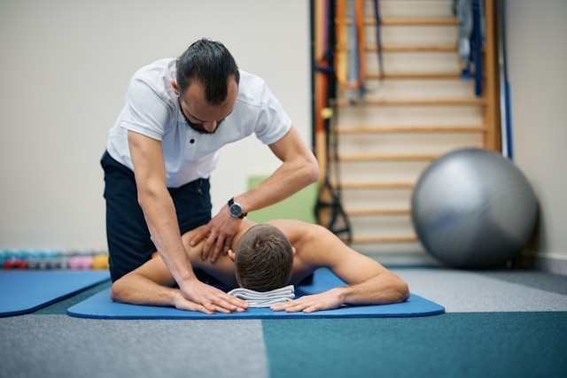 athletic-man-lying-with-face-down-while-physiotherapist