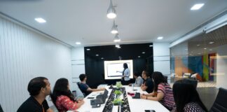 Why Is MaxMunus the Right Choice for Lenel OnGuard Training? people-sitting-at-the-table-looking-to-another-person-standing-in-front-of-them